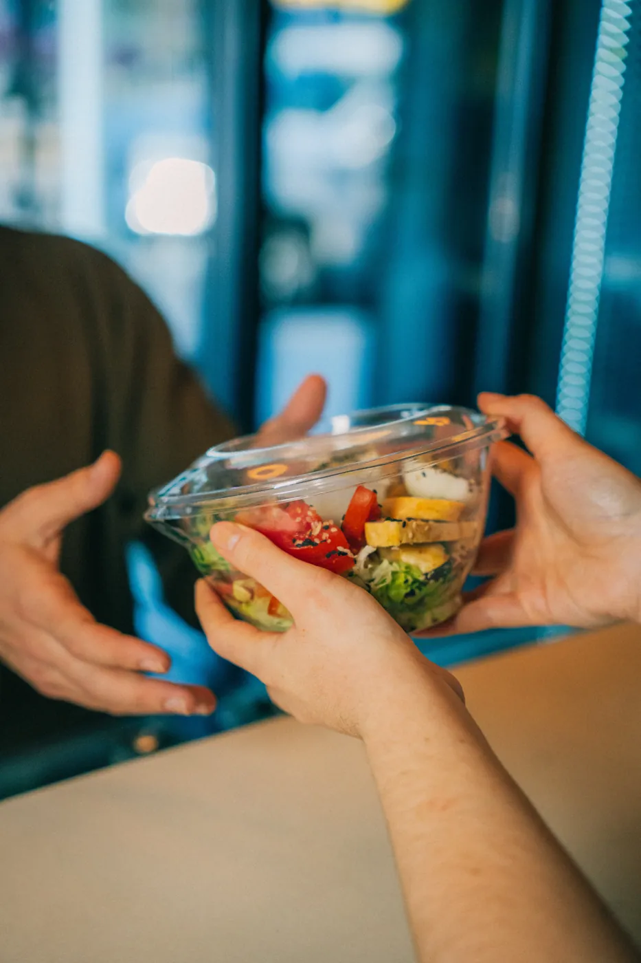 Entrega de un bowl de ensalada en el mostrador
