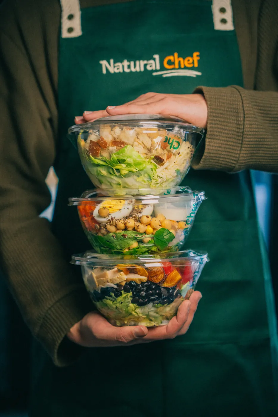 Integrante del equipo de Natural Chef con bowls de ensalada apilados